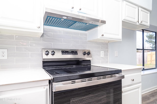 kitchen with backsplash, ventilation hood, wood-type flooring, white cabinets, and stainless steel range with electric cooktop