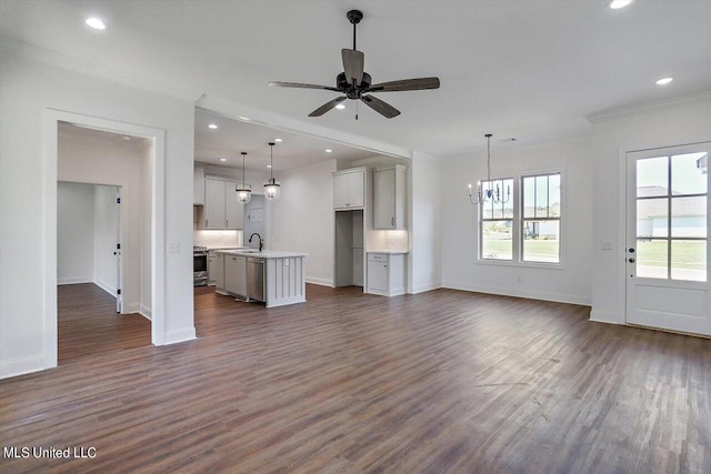 unfurnished living room featuring ceiling fan with notable chandelier, dark hardwood / wood-style flooring, ornamental molding, and sink