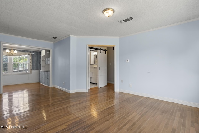 unfurnished room featuring a textured ceiling, a notable chandelier, crown molding, and dark hardwood / wood-style flooring