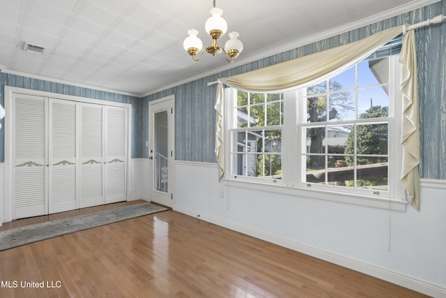 interior space with a chandelier, hardwood / wood-style floors, and ornamental molding