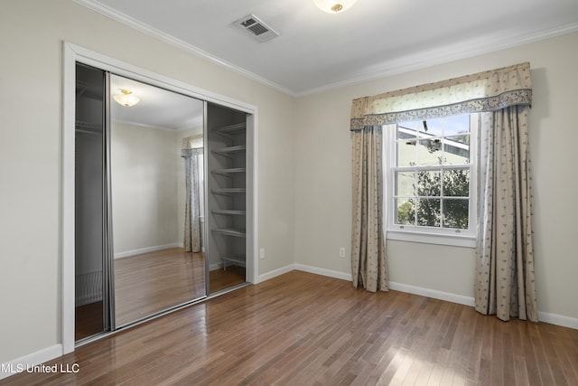 unfurnished bedroom with ornamental molding, hardwood / wood-style floors, and a closet