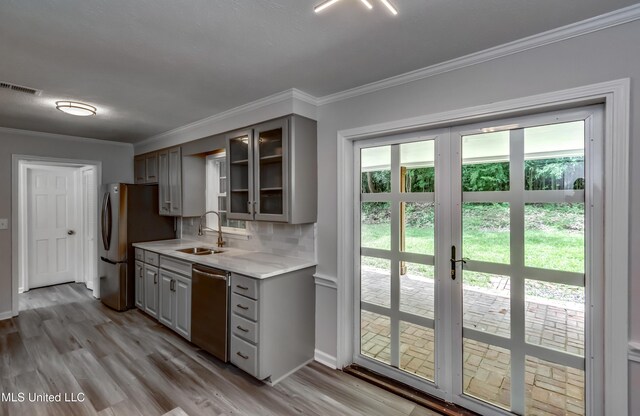 767 Sherwood Dr, Jackson, MS 39216 - kitchen featuring gray cabinetry, stainless steel appliances, a sink, ornamental molding, and glass insert cabinets