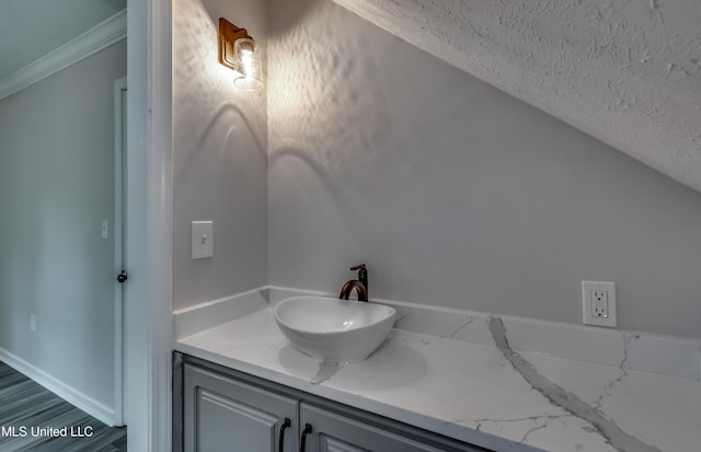 767 Sherwood Dr, Jackson, MS 39216 - bathroom with ornamental molding, a textured ceiling, vanity, baseboards, and wood finished floors