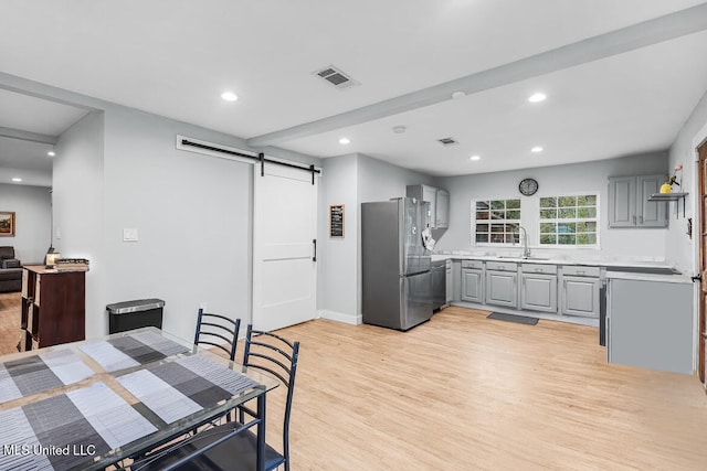 dining room with light wood-type flooring, a barn door, and sink