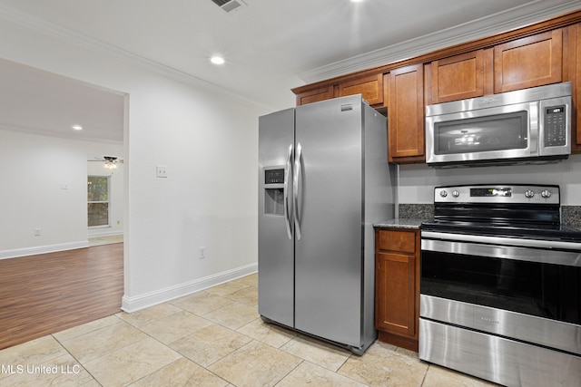 kitchen with ceiling fan, dark stone countertops, light wood-type flooring, ornamental molding, and stainless steel appliances