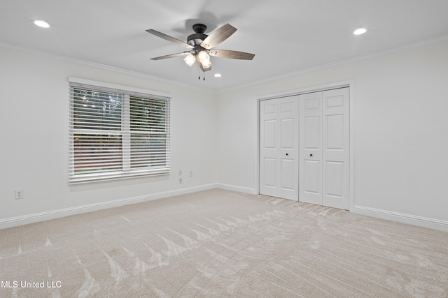 unfurnished bedroom with ceiling fan, light colored carpet, ornamental molding, and a closet