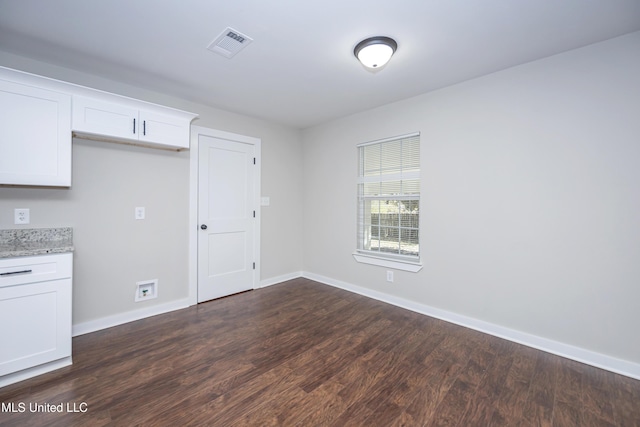 kitchen with white cabinetry, dark wood-type flooring, and light stone counters