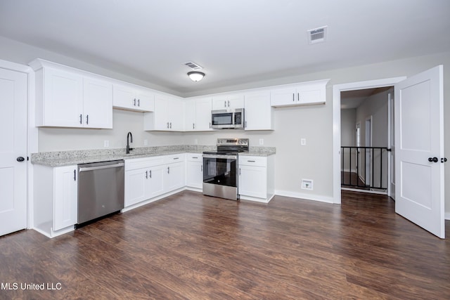 kitchen featuring white cabinetry, sink, dark wood-type flooring, stainless steel appliances, and light stone counters