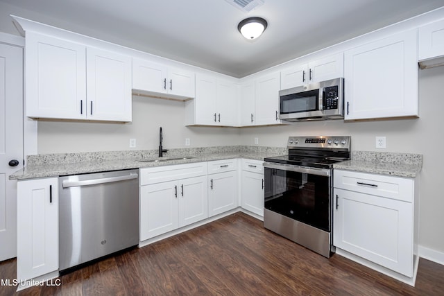 kitchen with light stone countertops, sink, dark wood-type flooring, white cabinets, and appliances with stainless steel finishes