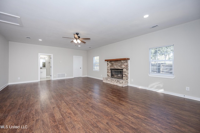 unfurnished living room featuring dark hardwood / wood-style floors, a brick fireplace, and ceiling fan