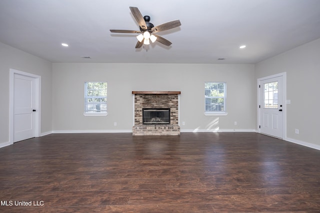 unfurnished living room featuring ceiling fan, dark hardwood / wood-style floors, and a brick fireplace