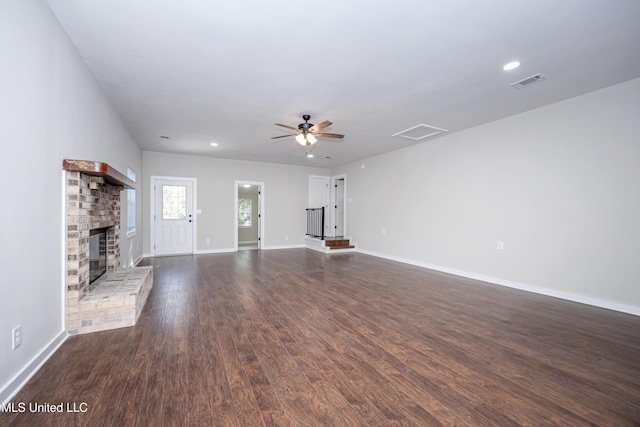 unfurnished living room featuring ceiling fan, a fireplace, and dark wood-type flooring