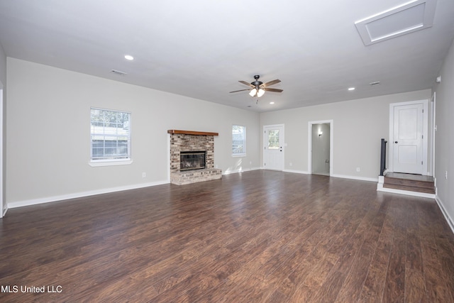 unfurnished living room featuring a brick fireplace, ceiling fan, and dark wood-type flooring