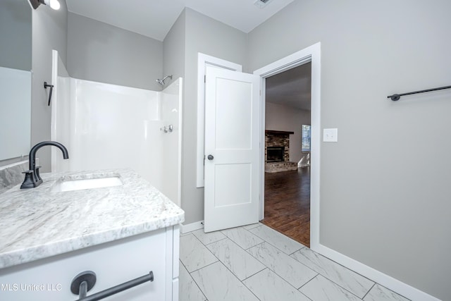 bathroom with vanity, a shower, and a fireplace