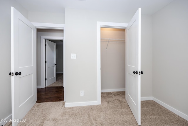 unfurnished bedroom with a closet and light colored carpet