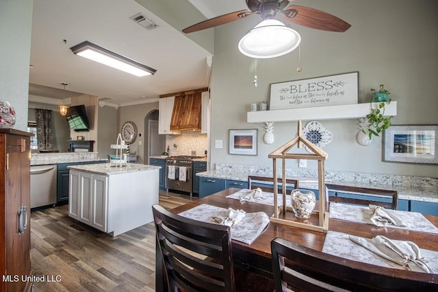 kitchen with decorative light fixtures, appliances with stainless steel finishes, dark hardwood / wood-style flooring, a kitchen island, and decorative backsplash