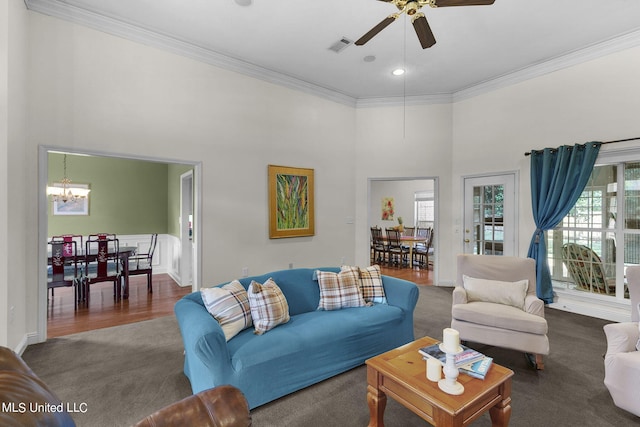 carpeted living room featuring ornamental molding, a high ceiling, and ceiling fan with notable chandelier