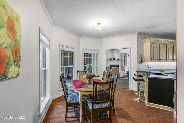 dining room featuring crown molding, a textured ceiling, sink, and dark hardwood / wood-style flooring