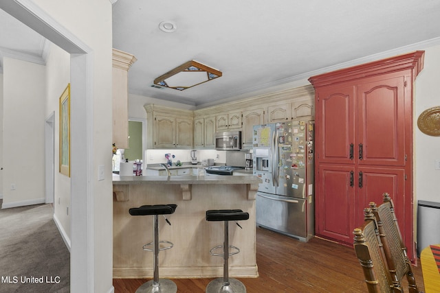 kitchen featuring appliances with stainless steel finishes, a kitchen bar, dark hardwood / wood-style flooring, kitchen peninsula, and crown molding