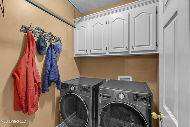 laundry room with washer and clothes dryer, a textured ceiling, and cabinets