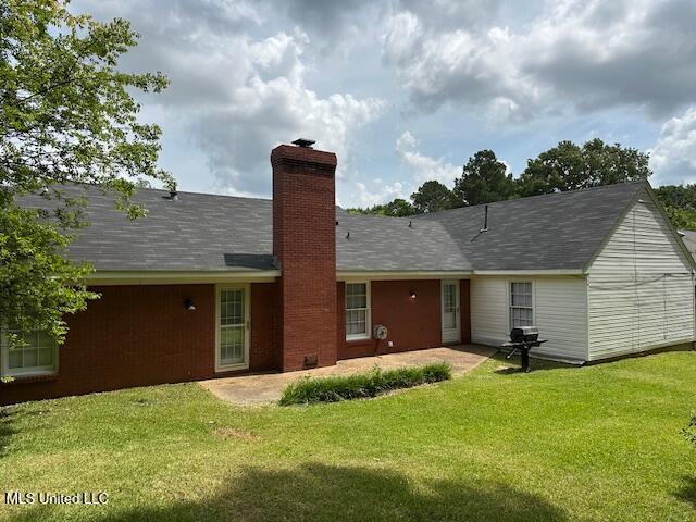 1613 Springridge Dr, Jackson, MS 39211 - back of house featuring a chimney, a patio area, and a lawn