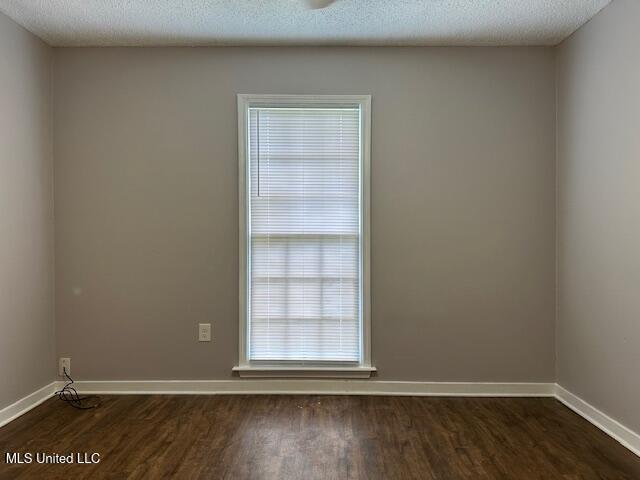 1613 Springridge Dr, Jackson, MS 39211 - empty room with dark wood finished floors, baseboards, and a textured ceiling