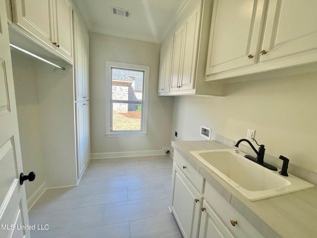 clothes washing area with cabinets, light tile patterned floors, hookup for a washing machine, hookup for an electric dryer, and sink