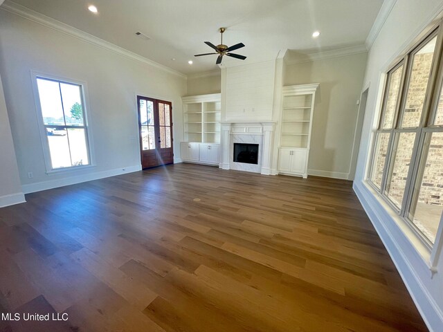 unfurnished living room featuring french doors, dark wood-type flooring, crown molding, a fireplace, and ceiling fan