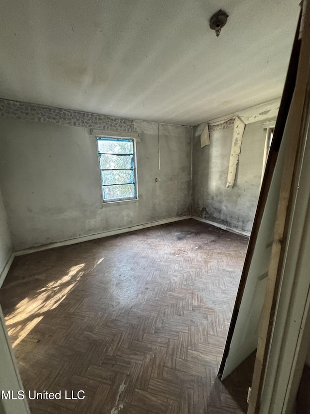 empty room featuring dark parquet flooring and a textured ceiling