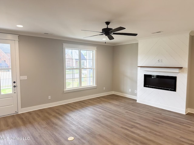 unfurnished living room featuring baseboards, ornamental molding, visible vents, wood finished floors, and a fireplace