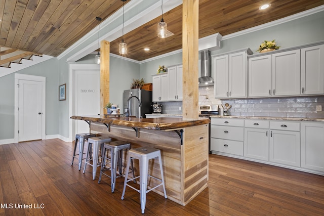 kitchen with tasteful backsplash, wall chimney range hood, a kitchen bar, ornamental molding, and wooden ceiling