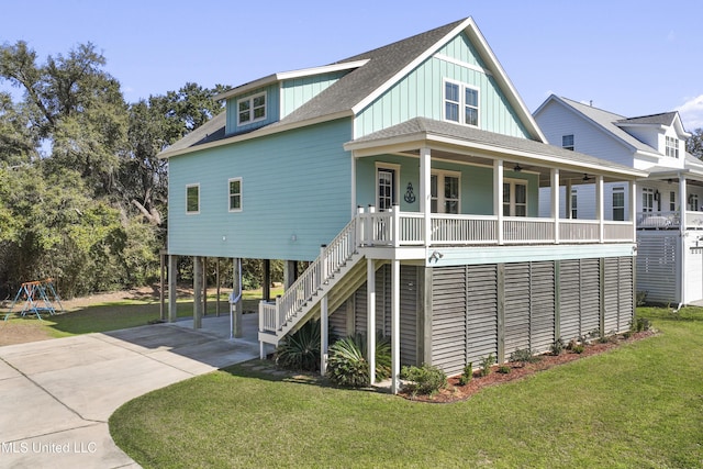 beach home with a porch, concrete driveway, stairs, and a front lawn