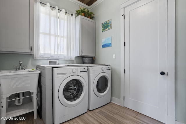 washroom featuring light wood-style flooring, cabinet space, washing machine and dryer, and crown molding