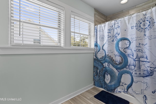 full bathroom featuring a shower with curtain, baseboards, and wood finished floors