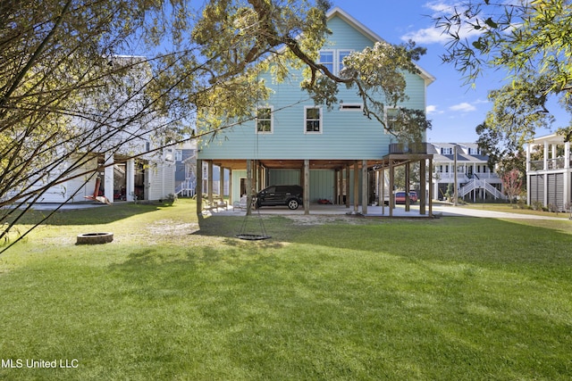 back of house with a yard, a carport, stairway, and an outdoor fire pit