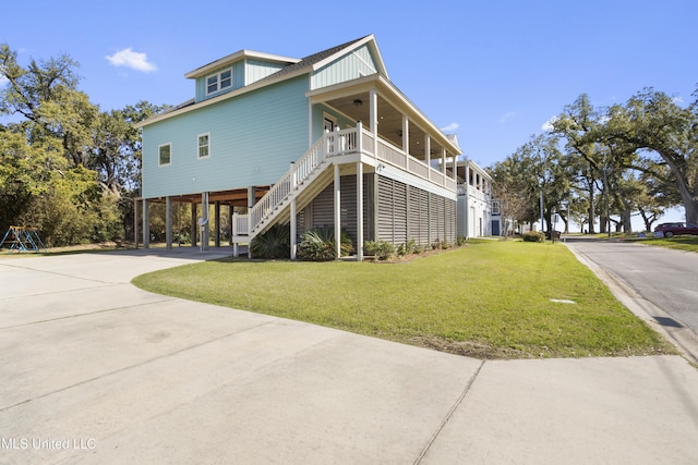 view of front facade with stairs, a front yard, covered porch, a carport, and driveway