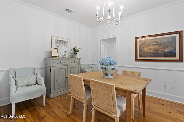 dining space with light wood-type flooring, visible vents, crown molding, and a notable chandelier