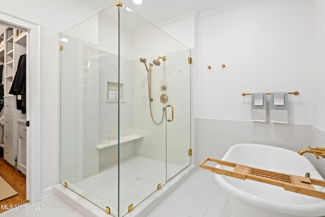 bathroom with a freestanding bath, ornamental molding, tile patterned flooring, and a shower stall