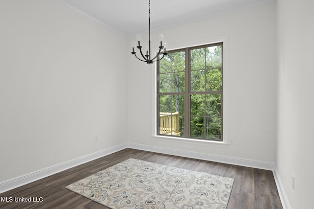 unfurnished room featuring baseboards, an inviting chandelier, ornamental molding, and dark wood finished floors