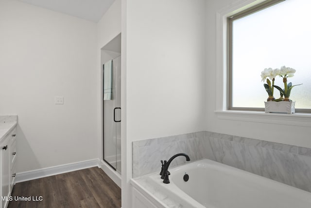 bathroom with vanity, wood finished floors, baseboards, a bath, and a shower stall