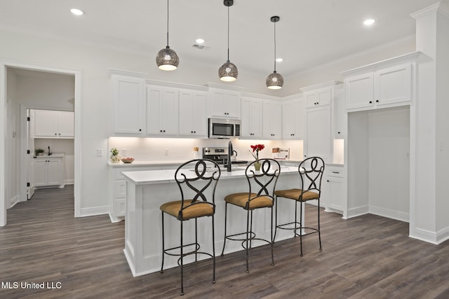 kitchen featuring white cabinets, appliances with stainless steel finishes, ornamental molding, and light countertops