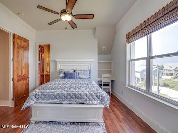 bedroom featuring multiple windows, wood finished floors, baseboards, and ornamental molding