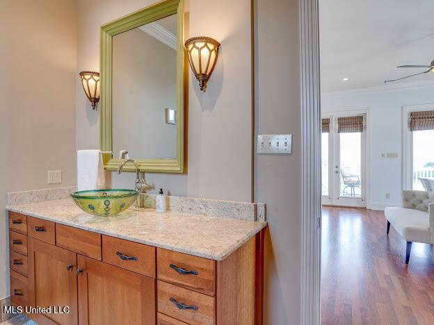 bathroom with ornamental molding, wood finished floors, baseboards, ceiling fan, and vanity