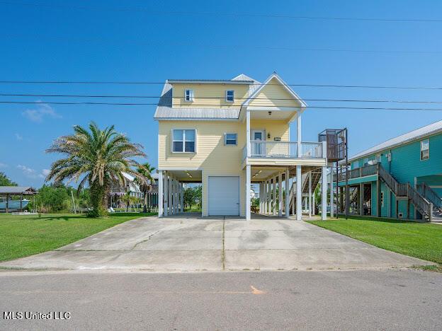 raised beach house with a front lawn, stairway, a porch, a garage, and a carport