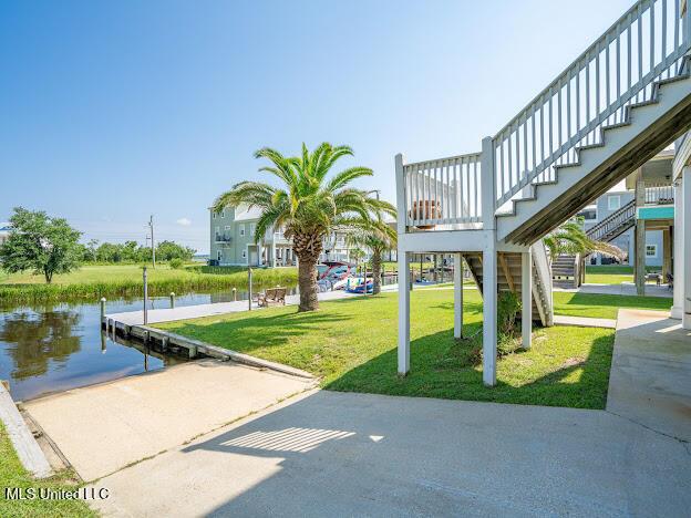 view of property's community with a yard, a water view, a dock, and stairway