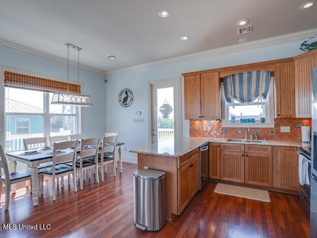 kitchen with visible vents, a peninsula, a sink, dark wood-type flooring, and crown molding