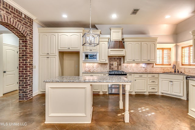 128 Amethyst Ln, Brandon, MS 39047 - kitchen featuring appliances with stainless steel finishes, a sink, a center island, tasteful backsplash, and light stone counters