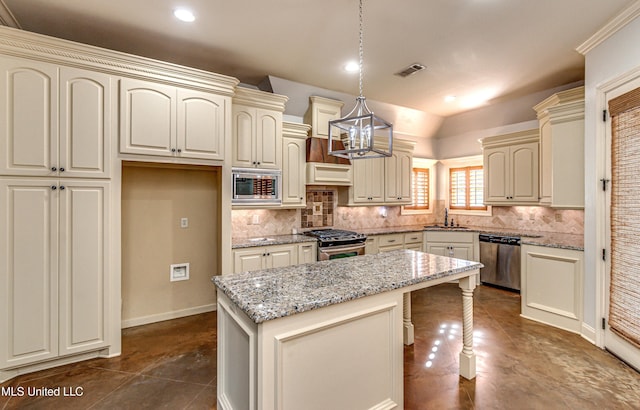 128 Amethyst Ln, Brandon, MS 39047 - kitchen with stainless steel appliances, a sink, cream cabinets, tasteful backsplash, and a kitchen island
