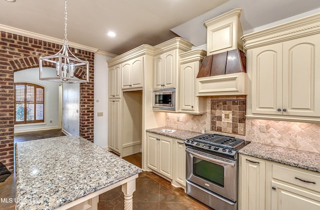 128 Amethyst Ln, Brandon, MS 39047 - kitchen featuring cream cabinets, appliances with stainless steel finishes, a chandelier, light stone counters, and crown molding