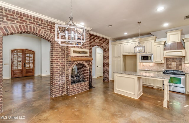 128 Amethyst Ln, Brandon, MS 39047 - kitchen featuring appliances with stainless steel finishes, cream cabinetry, arched walkways, ornamental molding, and backsplash